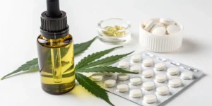 CBD oil bottle with cannabis leaf and ibuprofen tablets
