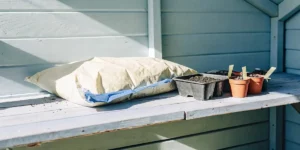 Starter soil kit with small pots and tray placed on a wooden garden shelf.
