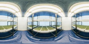 Panoramic view of a sterile indoor cultivation room with multiple tiered shelves holding small green plants under artificial lights.