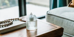 A sleek quartz carb cap resting on a wooden table beside beads and a notebook.